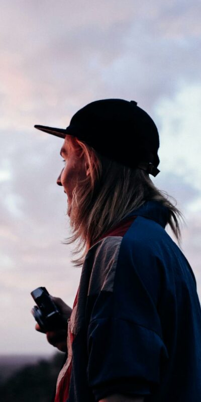 Young traveler in cap under cloudy sky